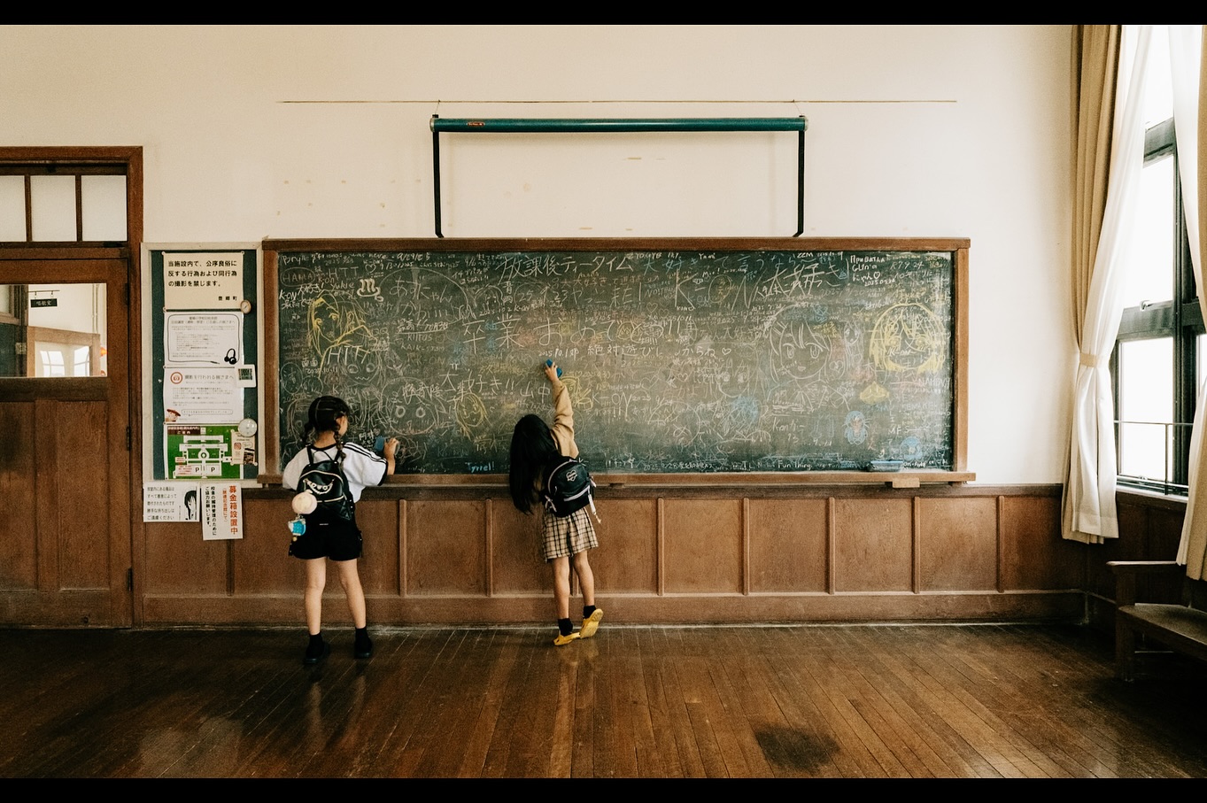 Two children writing on a blackboard in an old Japanese classroom